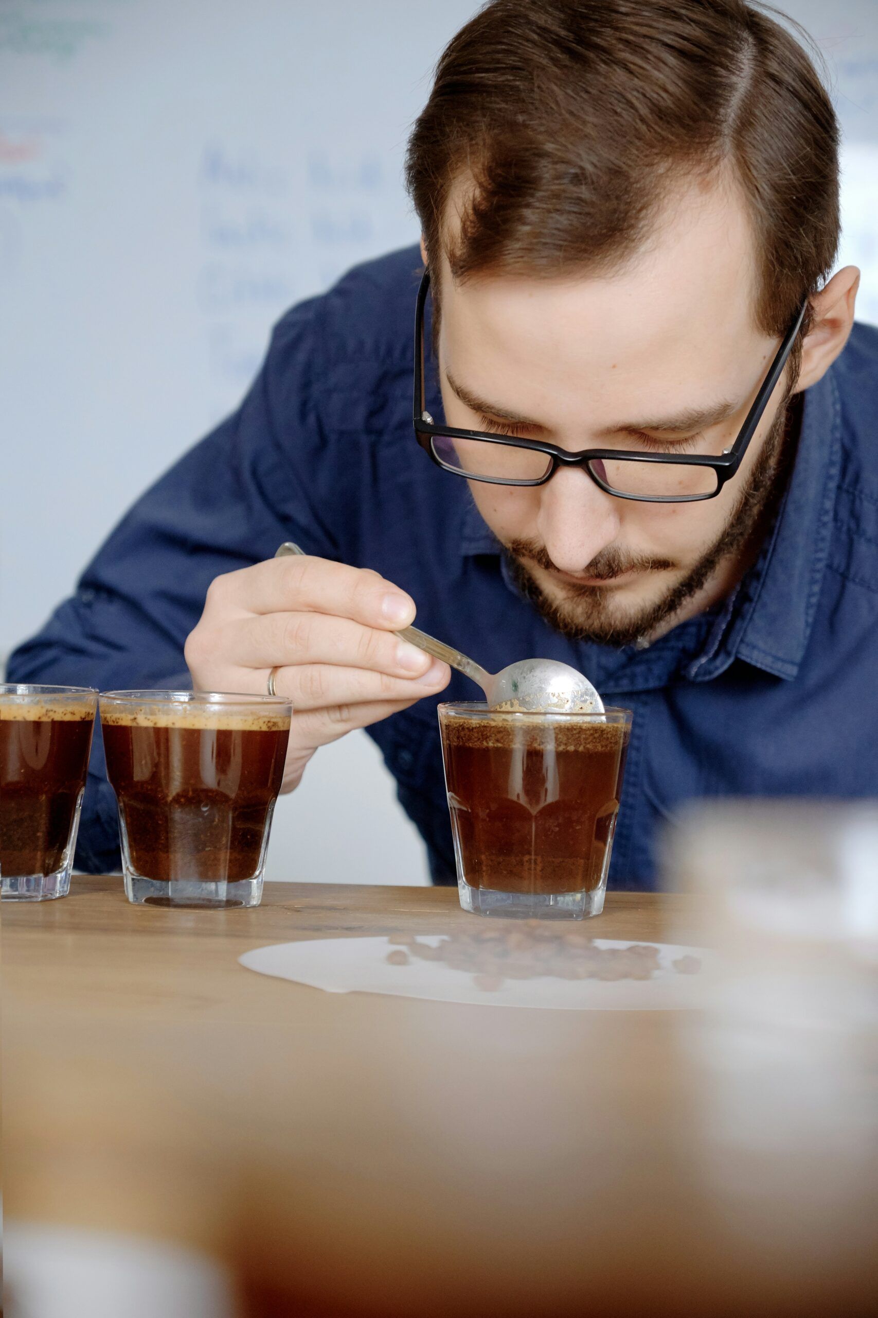 Man smelling freshly brewed coffee in glass cup, examining coffee taste and flavour at coffee cupping test
